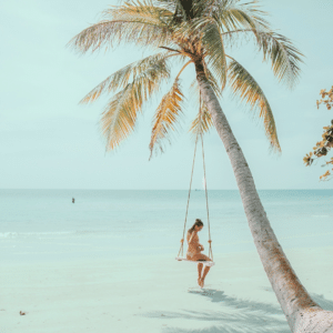 Strand mit Palme und Frau auf Schaukel